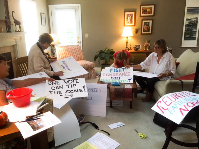 Members of the group, Defending Democracy create signs for rally